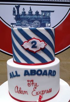 a train themed birthday cake with the number two on it's side and an all aboard sign in the background