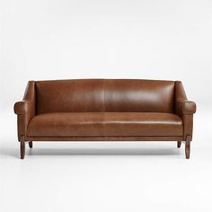 a brown leather couch sitting on top of a white floor next to a wooden frame