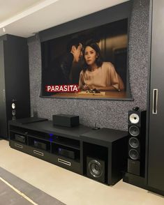 an entertainment center with speakers and a large screen on the wall in front of it