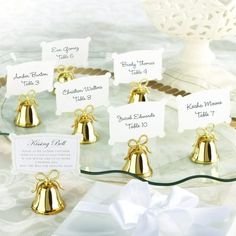 small gold bell place cards on a glass platter with a white bow tied around it