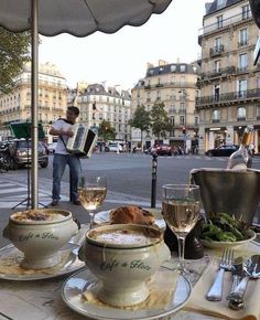 an outdoor table with food and wine on it in the middle of a city street