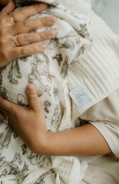 a close up of a person holding a baby wrapped in a blanket with the word hello on it