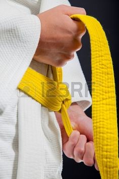 a person wearing a white robe and yellow belt