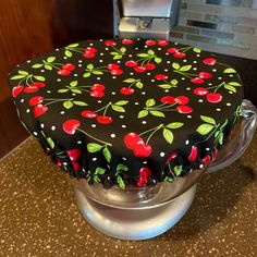 a cake covered in black and red cherries on top of a metal stand,