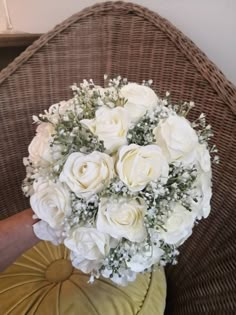 a bouquet of white flowers sitting on top of a chair next to a pillow and cushion