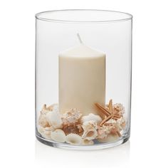 a white candle with shells and starfish in a clear glass container on a white background