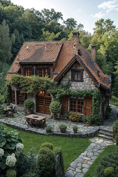 a stone house with lots of greenery on the roof and windows, surrounded by lush green trees