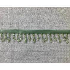 a piece of green fabric with fringes and beads on the end, sitting on top of a gray cloth