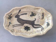 a decorative plate with an image of a running rabbit on it's side and yellow dots around the edges