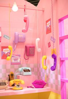 an assortment of telephones and phones on display in a pink room with checkered walls