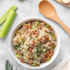 a white bowl filled with food next to celery and spoons on top of a table