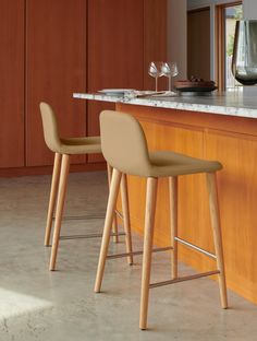 two stools sitting in front of a counter with wine glasses on top of it