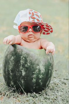 a baby wearing sunglasses and a hat sitting in a watermelon