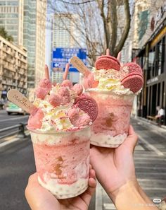 two ice cream sundaes with oreo cookies on top are being held up in the air