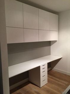 an empty office space with white cabinets and drawers on the wall, along with hardwood flooring