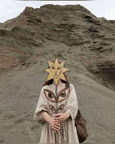 a woman with a mask on her head standing in front of a mountain