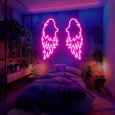 two angel wings on the wall above a bed in a room with purple lighting and potted plants