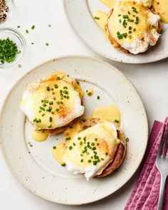 two plates with eggs and bacon on them next to a fork, knife and spoon