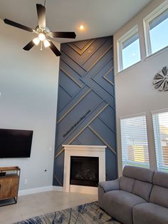 a living room with a couch, fireplace and ceiling fan in front of a flat screen tv mounted on the wall