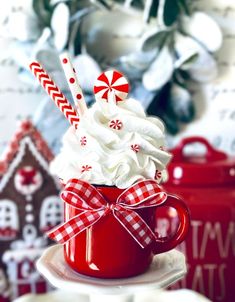 a red mug filled with whipped cream and candy canes on top of a plate