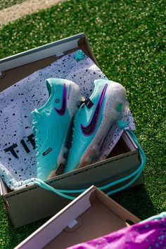 a pair of blue and white nike shoes in a box on the ground with grass