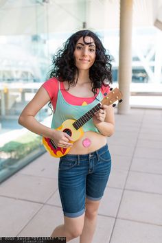 a woman holding a guitar and posing for the camera