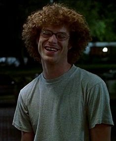 a man with curly hair and glasses smiles at the camera