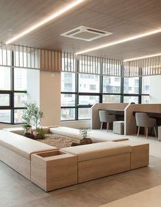 a living room filled with lots of furniture next to large windows and plants on the floor