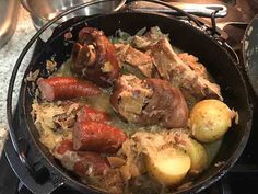 a pan filled with meat and potatoes on top of a stove