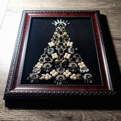 a christmas tree made out of beads on a wooden table with a framed picture in the middle