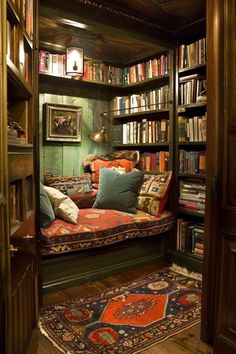 a room filled with lots of bookshelves covered in colorful pillows and rugs