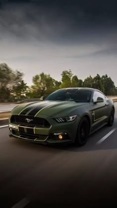 a green ford mustang driving down the road