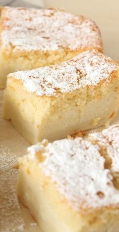 three pieces of cake sitting on top of a wooden table covered in powdered sugar