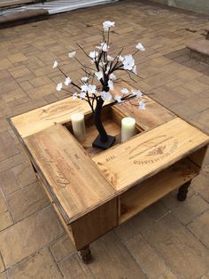 a coffee table made out of pallet wood with a vase and candles on top