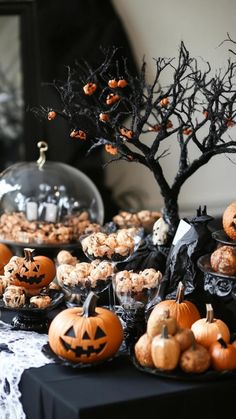 a table topped with lots of pumpkins next to a tree and other food items