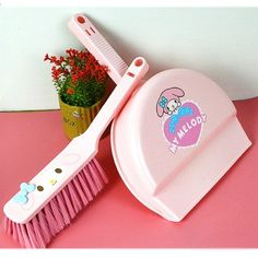 a pink toothbrush and comb sitting on top of a table next to a potted plant