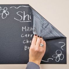 a person holding a knife over a blackboard with writing on it