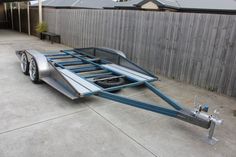 an aluminum trailer parked in front of a fenced area with no one around it