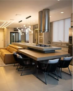 a modern kitchen with an island table surrounded by black chairs and brown leather couches