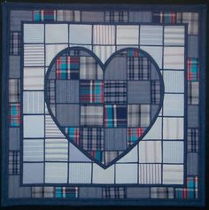 a heart made out of squares in blue and grey colors on a black frame with the shape of a patchwork heart