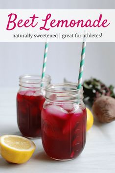 two mason jars filled with beet lemonade, sitting next to sliced lemons