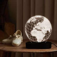 a light up globe sitting on top of a wooden table next to shoes and a pair of shoes