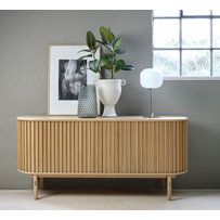 a wooden sideboard with two vases and a plant on it next to a window