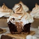 some cupcakes with frosting and marshmallows on the top one