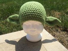 a green crocheted hat on top of a white head mannequin's head