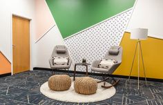 two chairs and a table in front of a wall with an abstract design on it