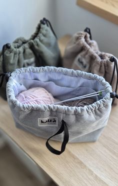 three bags sitting on top of a wooden table next to each other and one has a cloth bag in it