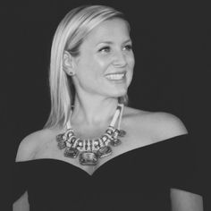 a woman in a black dress smiles at the camera while wearing a necklace with beads