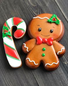 two decorated cookies sitting on top of a wooden table next to a candy cane and peppermink