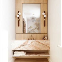 a bathroom with marble counter tops and wooden cabinets, along with a large mirror on the wall